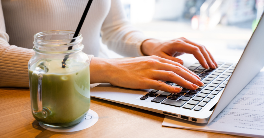 Person at a desk typing and studying Japanese with an ice matcha latte in a glass nearby.